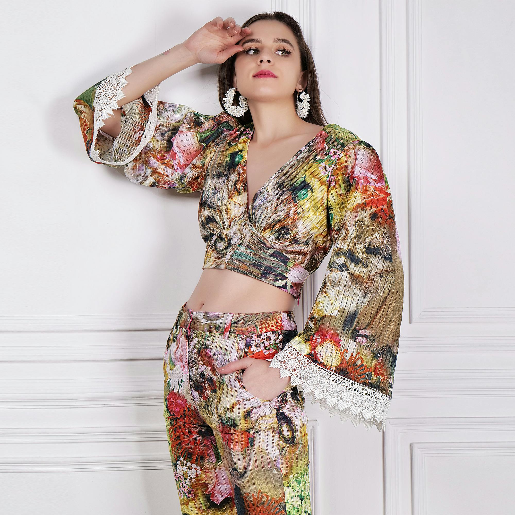 Stylish woman wearing a colorful floral outfit posing elegantly in a studio setting.