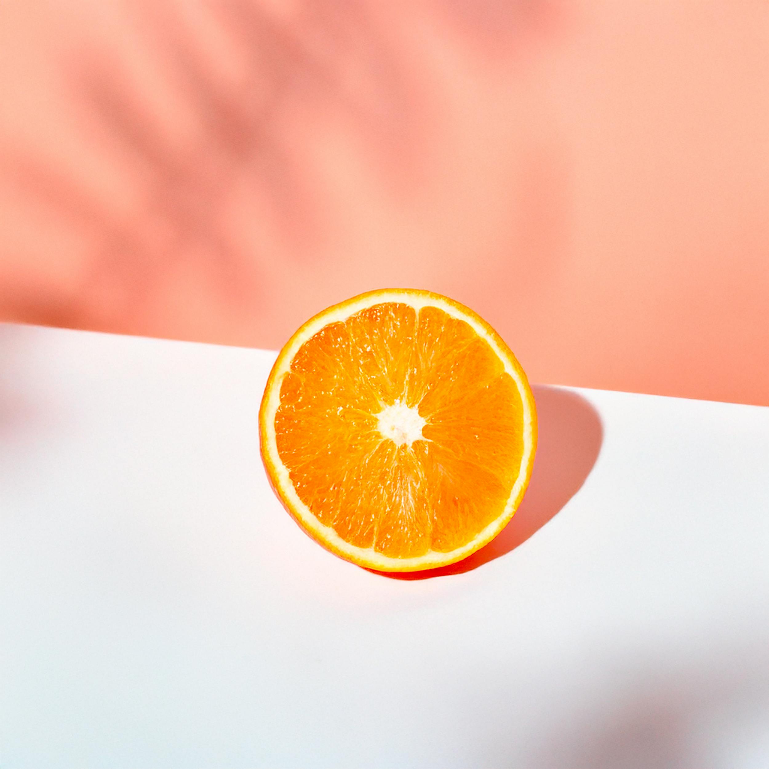 Bright orange slice with a pastel backdrop, ideal for fresh, modern designs.