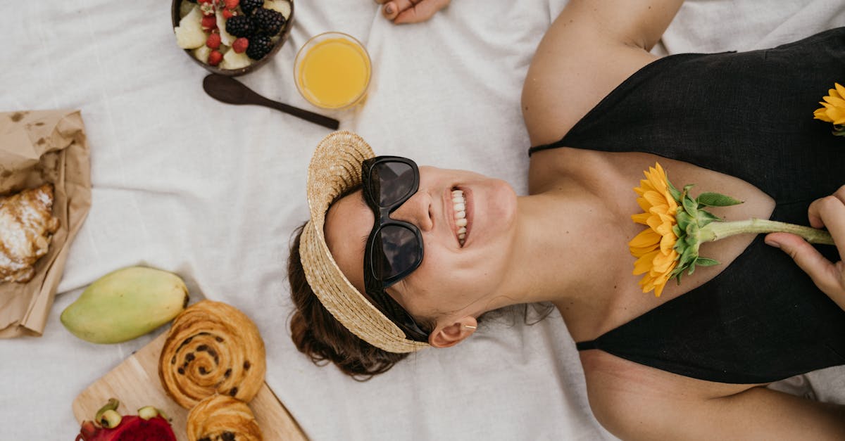 Woman enjoying a summer picnic with fruit, pastries, and orange juice on a sunny day.