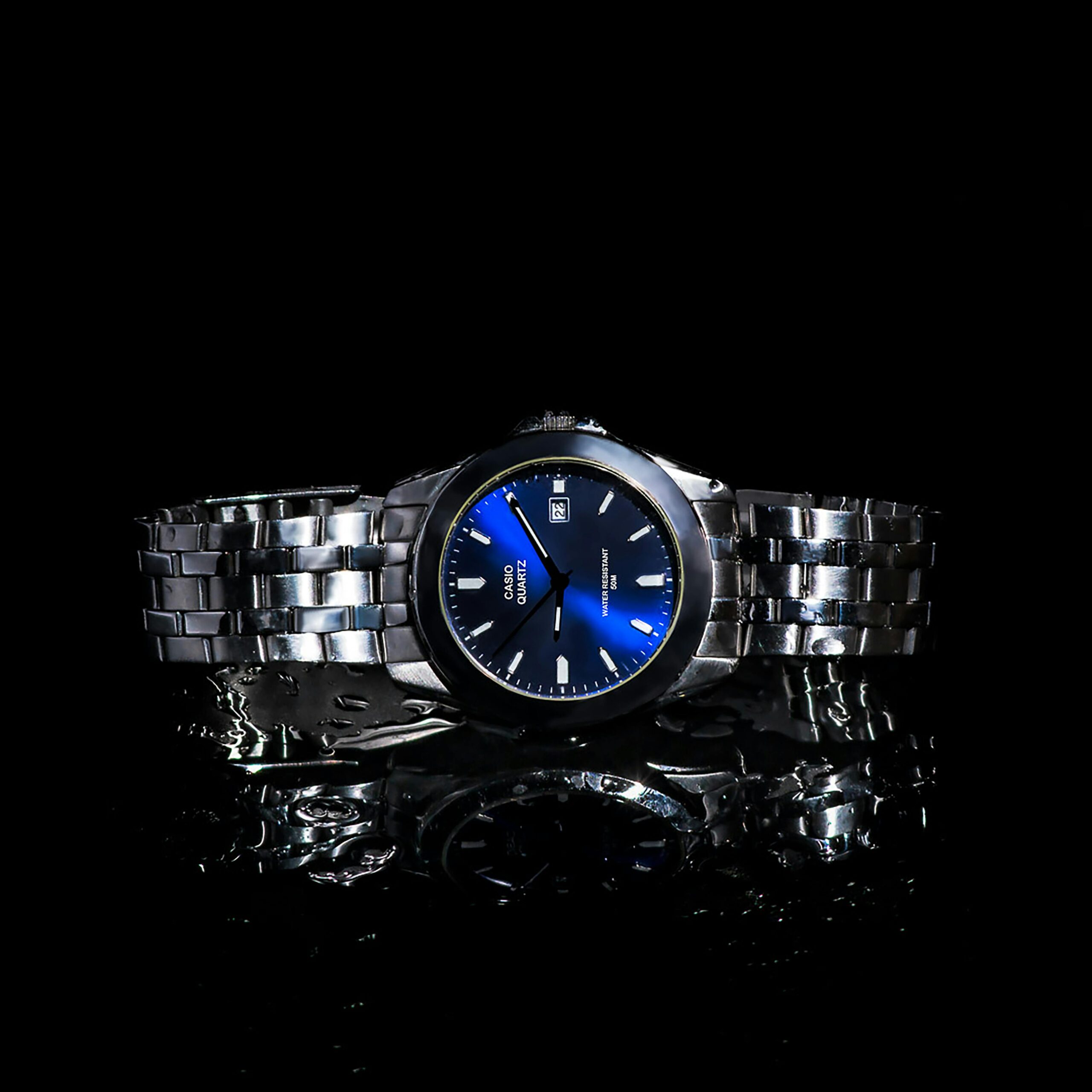 Stylish silver wristwatch on a reflective black surface, perfect for fashion and accessory themes.