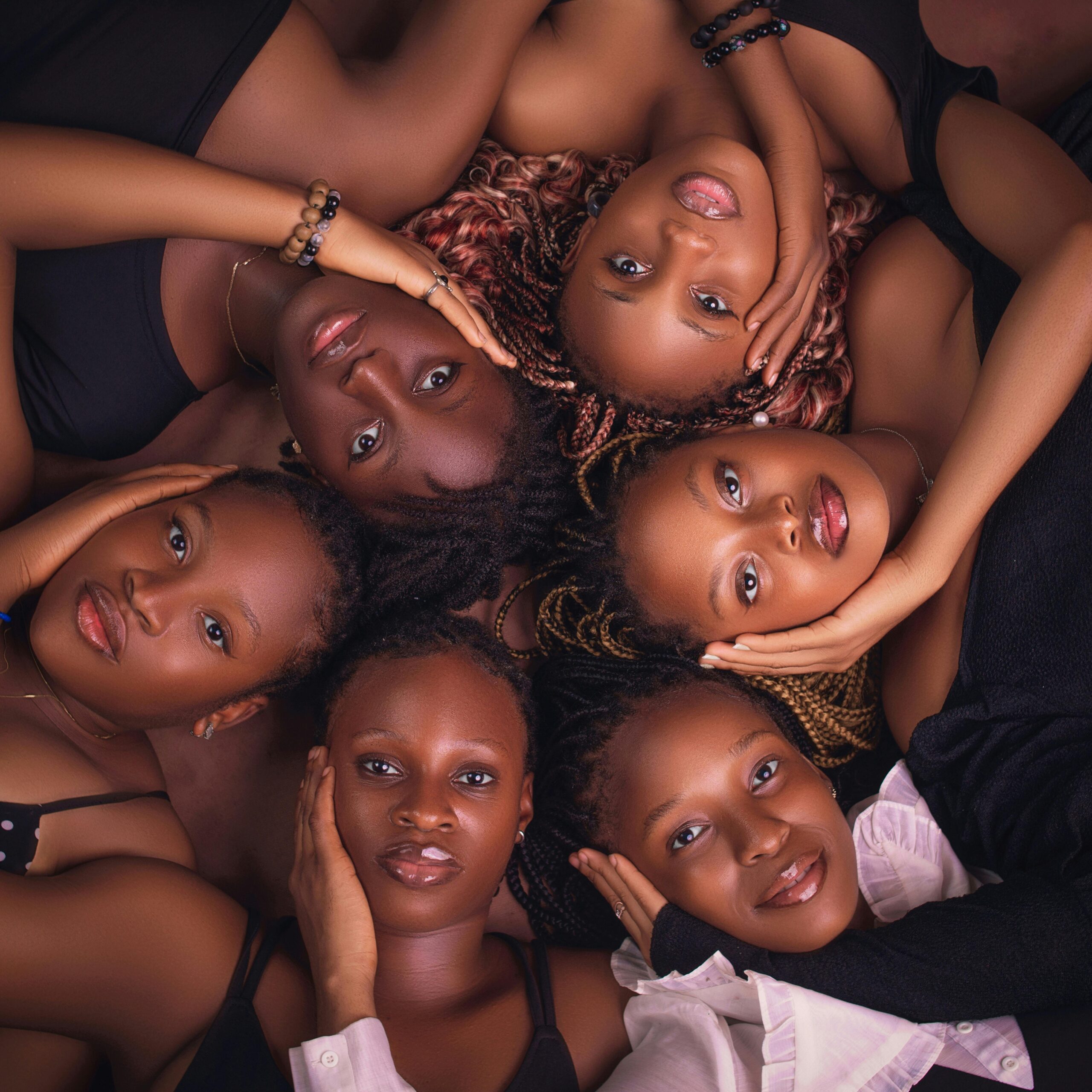 A captivating aerial shot of six diverse women lying together, exuding unity and elegance.