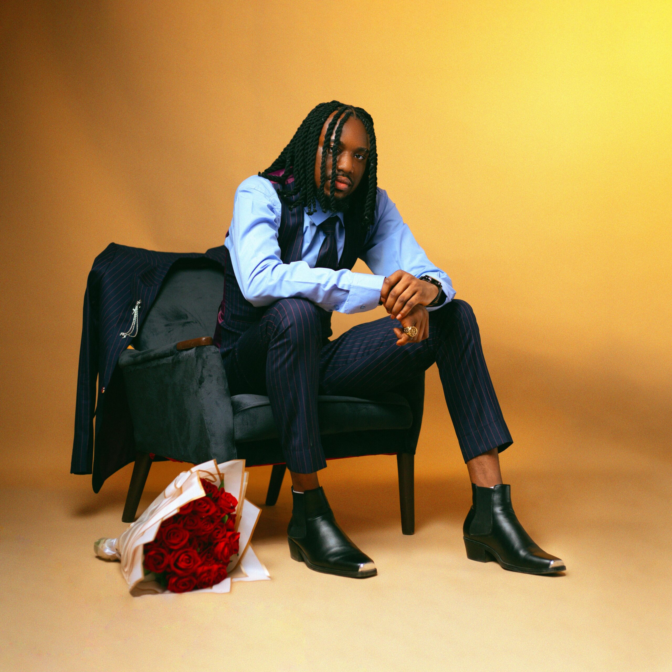 Elegant fashion portrait of a model sitting confidently with a bouquet of red roses on a chair.