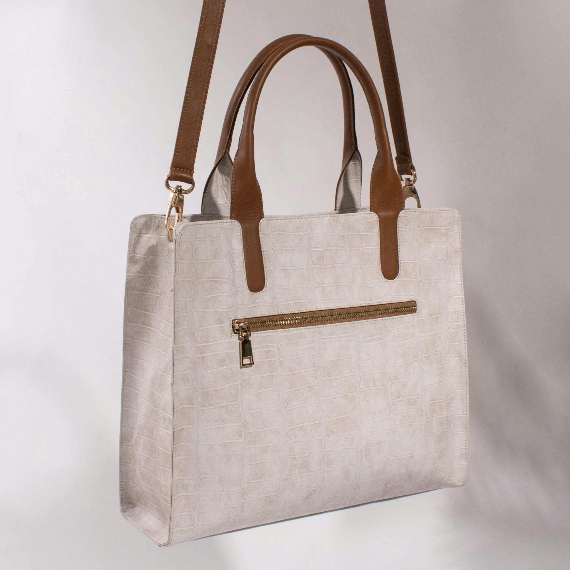 Sophisticated white handbag with brown leather straps, perfect for stylish outings.