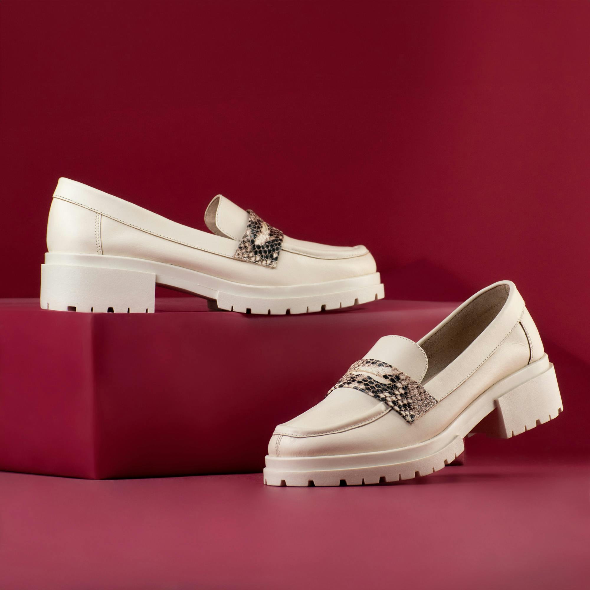 Elegant cream leather loafers with rugged soles and snake print detail, perfect for modern fashion.