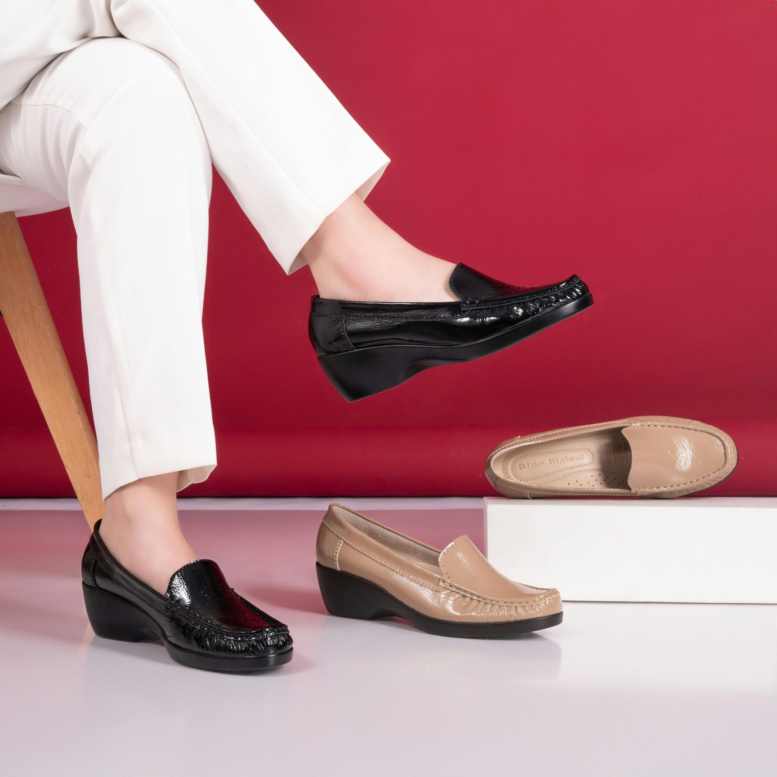 Elegant women's moccasins in black and beige highlighted against a red backdrop.