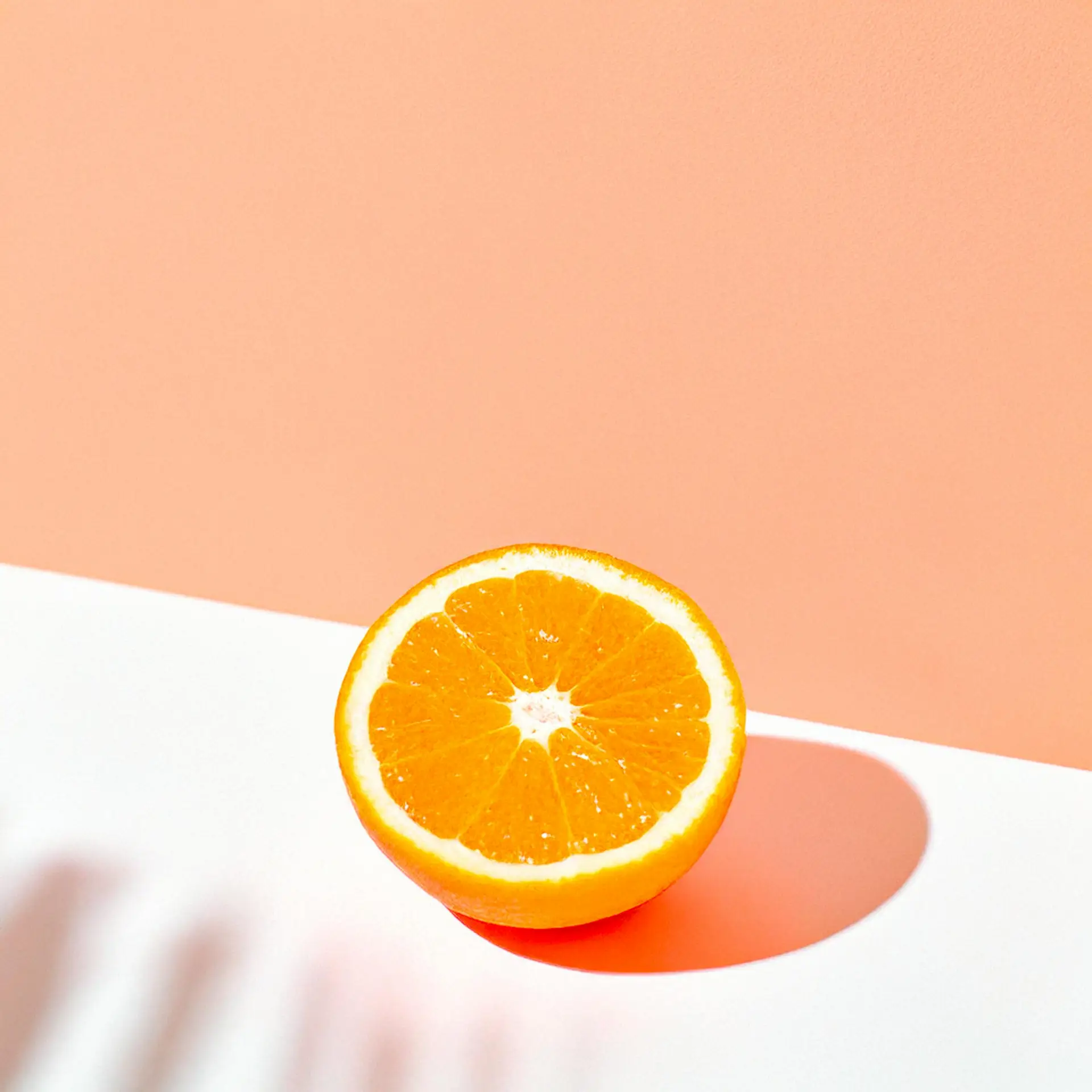 Bright orange slice on a salmon colored background with vibrant contrast.