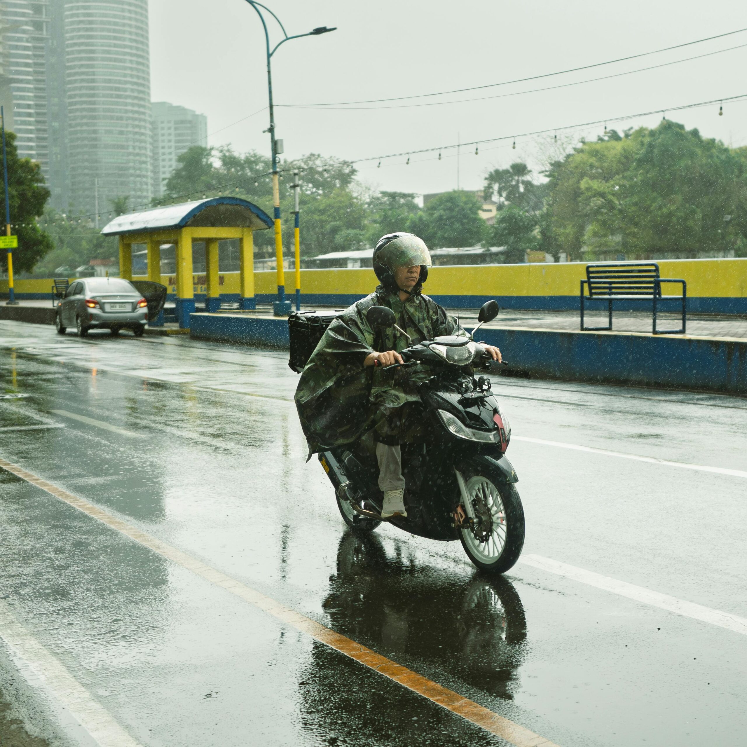A motorcyclist rides through rainy streets in Mandaluyong City, Philippines, showcasing urban life.