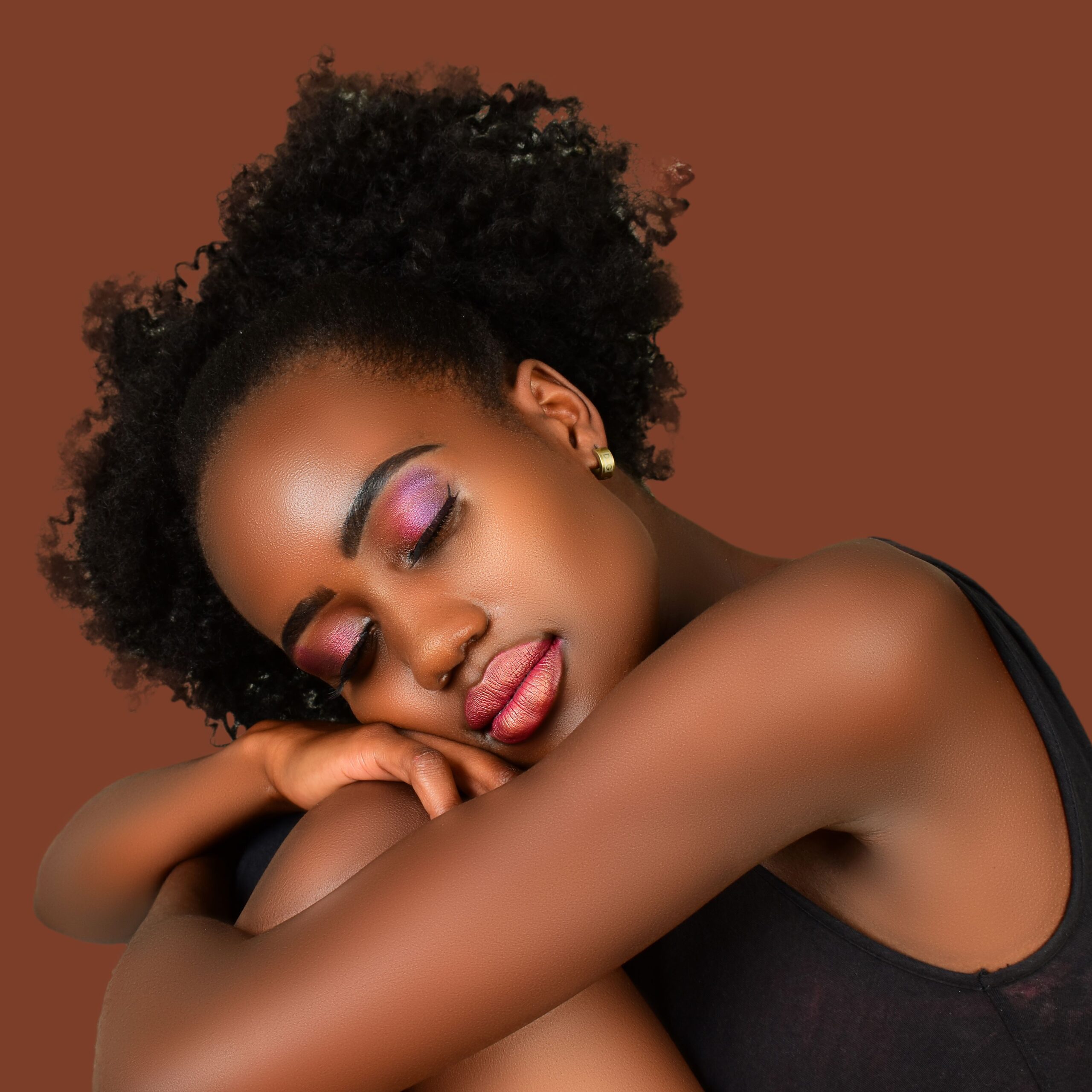 Close-up portrait of a woman with closed eyes, showcasing elegance and vibrant makeup.