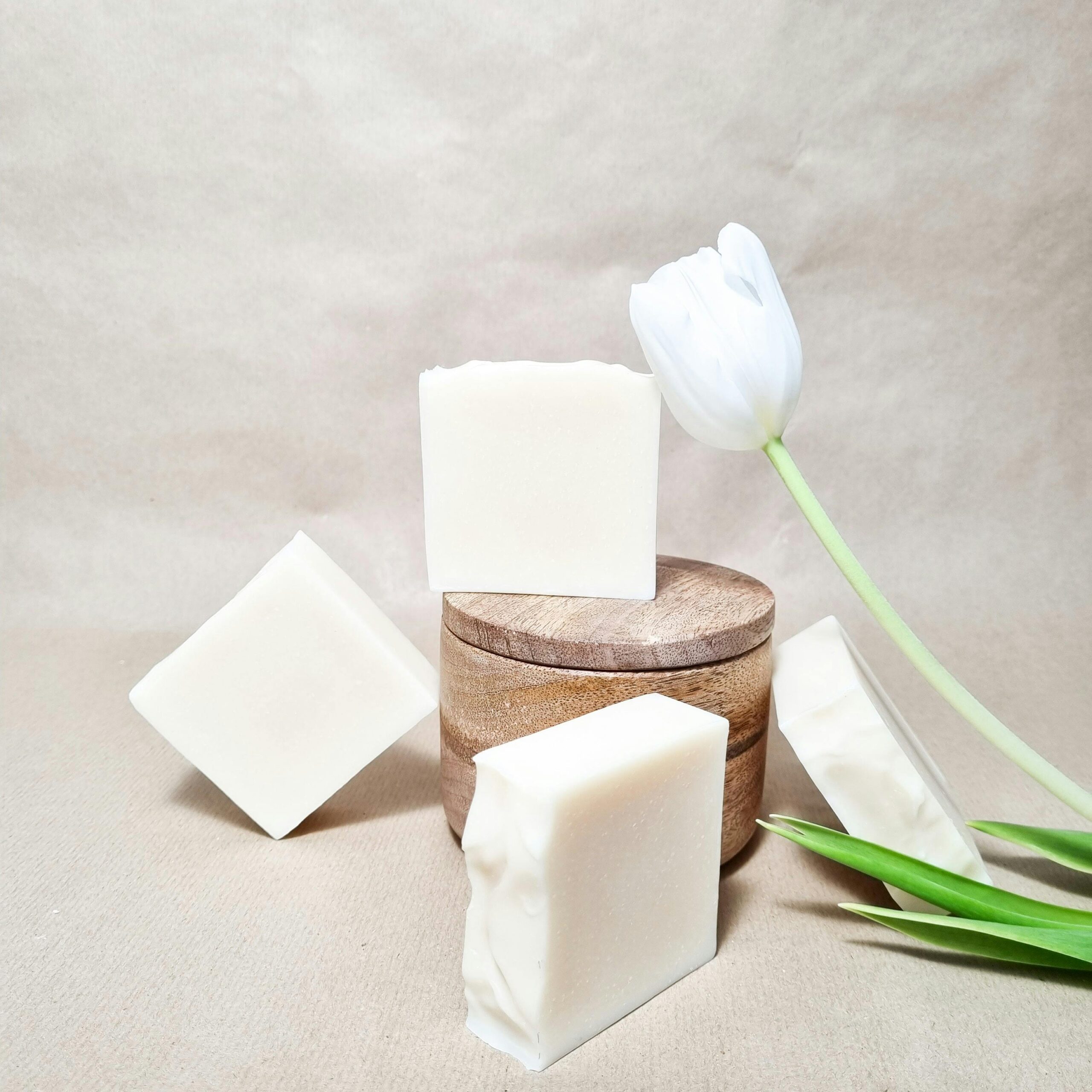 Artistic display of handmade natural soap bars with a white tulip, perfect for eco-conscious themes.