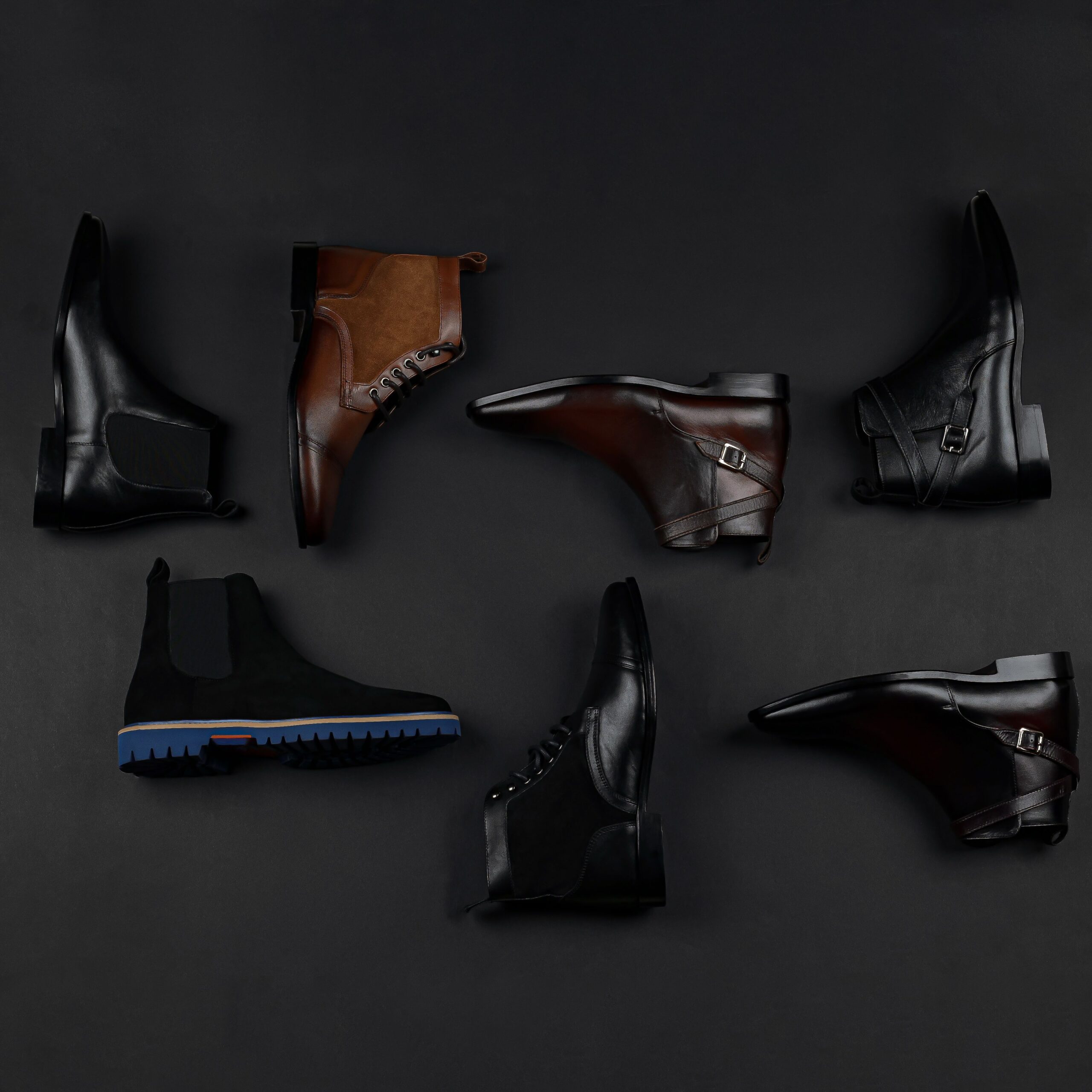 Stylish men's leather shoes arranged on a black background, showcasing various styles.